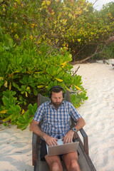 Remote Worker Using Laptop on Tropical Beach with Headphones