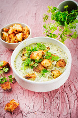 Chervil creamy blend vegetable soup with fresh made roasted white bread croutons served as close-up in a design bowl