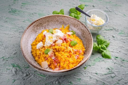 Risotto allo zafferano e prosciutto - traditional saffron risotto alla milanese with prosciutto crudo dry cured ham and parmesan