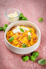Risotto allo zafferano e prosciutto - traditional saffron risotto alla milanese with prosciutto crudo dry cured ham and parmesan served as close-up in a design bowl