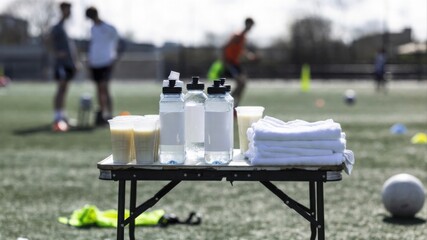 Hydration station with water bottles and towels at sports field
