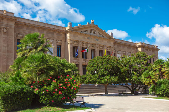 Palazzo Zanca in Messina from Sicily Italy. Grand classical style building adorned with flags, surrounded by lush greenery 