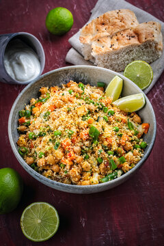 Couscous salad with chickpeas, green beans, carrots, green peas, flatbread and yogurt served as close-up in a design bowl