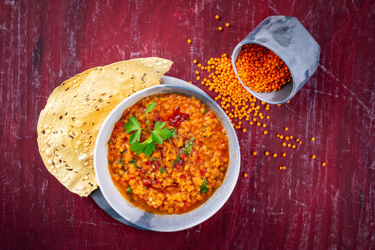 Indian dal fry red lentils with chili papadam served as top view in a design bowl