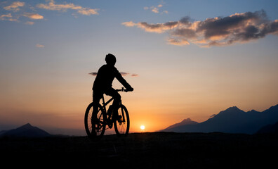 Cyclist Silhouette Riding At Sunset In Mountain Landscape
