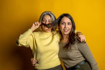 Mother and daughter sharing a playful moment, older woman creating a mustache with her hair while the younger woman smiles