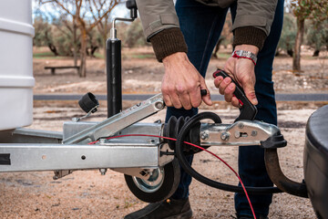 Hands engaging caravanning hitch, attaching leisure vehicle to travel for holidays or camping. Road trip preparation