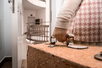 Person's hand grasping an old carry-on suitcase, symbolizing departure, adventure, and new experiences