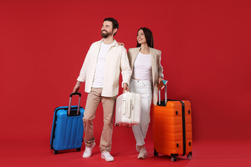 Happy couple with suitcases, passports and tickets on red background