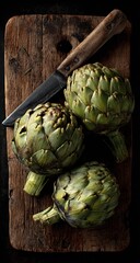 Obraz premium Three Fresh Green Artichokes on Rustic Wooden Board with Vintage Knife, Moody Dark Still Life.
