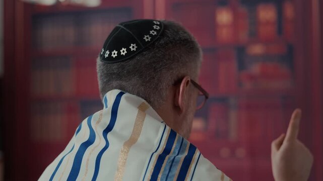 jewish Men from the back, his head is covered by a traditional jewish kippah with blue and gold stripes and tassels. Close up view