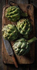 Fototapeta premium Moody Still Life of Fresh Green Artichokes and Knife on Rustic Wooden Board.