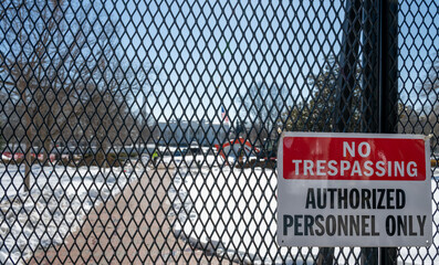 No trespassing sign displayed on a fence with snow coverage in the background at the United States...