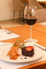 Vertical shot of grilled salmon with Venere rice and pepper sauce served at a restaurant table.
