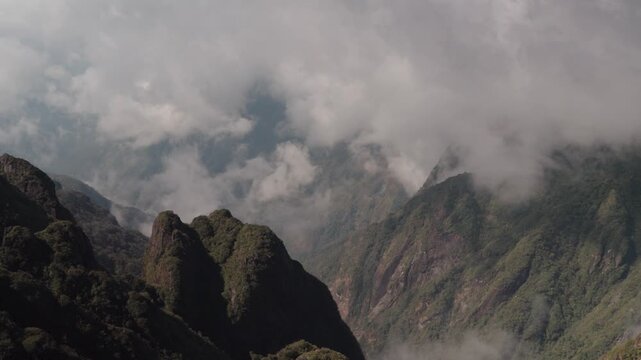 Clouds drift around rugged rocky cliffs at Fansipan Peak in Sapa, Vietnam, revealing dramatic high-altitude mountain scenery at the country&rsquo;s highest summit.