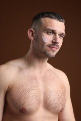 Fototapeta premium Handsome man with cream on his face against brown background
