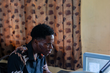 Fototapeta premium Young African student using a computer in school
