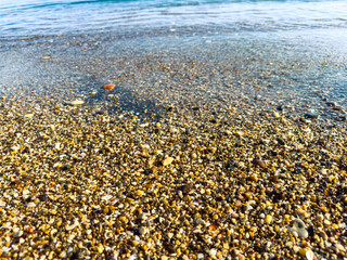 Obraz premium Water touches sandy shore as small waves roll in during sunny day at beach with clear sky above