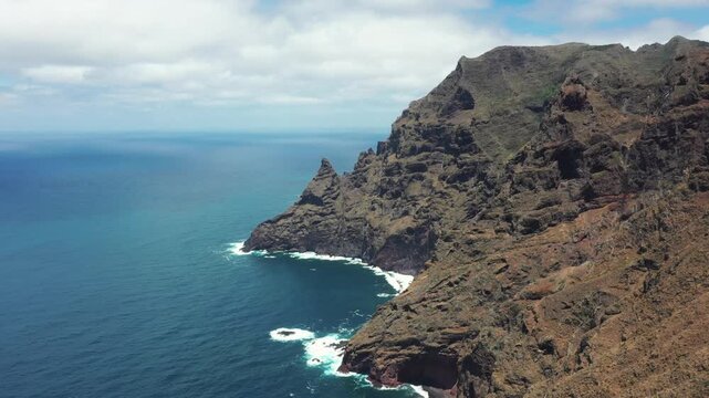 Aerial coastal flight over Tenerife cliffs approaching Baja de La Goleta rock formation from ocean side