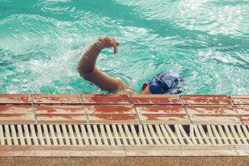 Asian child competing swimmer in the swimming pool
