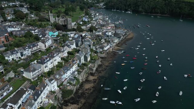 Coastal town with a church, terraced houses, and a harbor filled with boats.