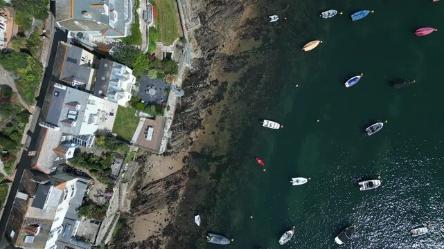 Coastal homes with a rocky shoreline and several boats on the water.