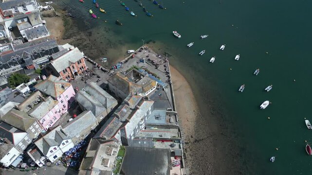 Aerial view of a coastal town with boats docked in the harbor and buildings lining the shore.