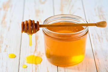 nature honey in a jar on a white wooden table, selective focus.