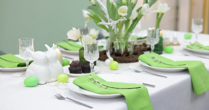 Easter celebration. Festive table setting with elegant dishware and flowers, closeup