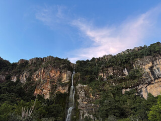 Scenic waterfall cascading over a rocky cliff under a blue sky with copy space - Wine Waterfall, Lara, Venezuela