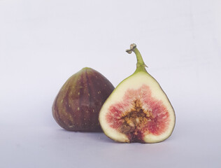 Two ripe figs on a white background. One is cut. Copy space.