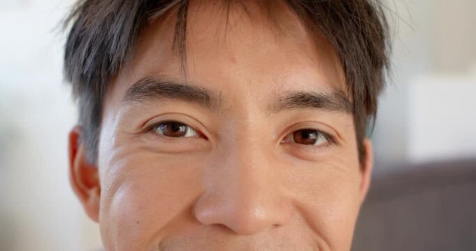 Asian man reacting to camera, making eye contact, blinking, winking and creating connection at home