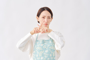 エプロンをつけた女性　ばつ印のジェスチャー　白背景