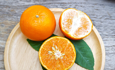 Oranges were placed on a wooden plate on the table.