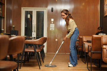 Female Worker Mopping Floor Surface in Coffee Shop © Sino Images Studio