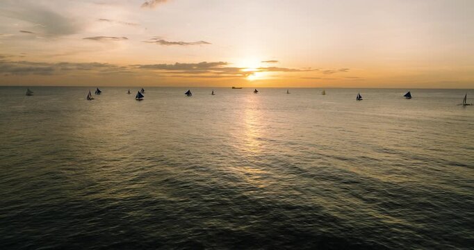 Flying over the sea with sunset reflection. Sailing boat in Boracay, Philippines.