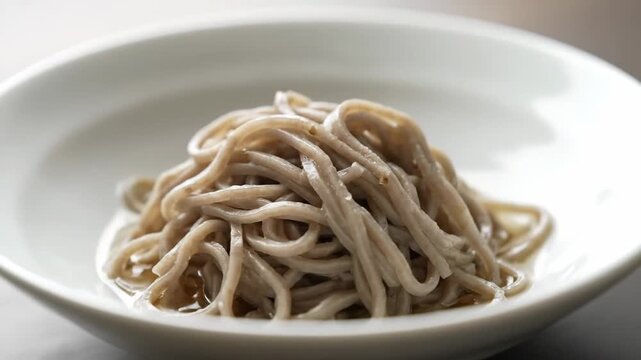Close-up studio shot of plain soba noodles (buckwheat ramen) served in a white bowl, representing healthy Asian cuisine and traditional Japanese food preparation.