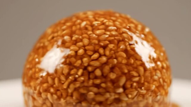 Macro Rotating Shot of Spherical Brittle Candy Made with Toasted Seeds and Clear Caramelized Sugar Glaze, a Delicious Traditional Sweet Confectionary Dessert