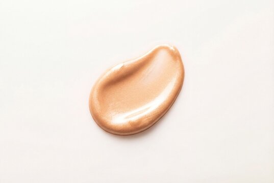 Golden beige liquid highlighter makeup smear isolated on a clean white background with glossy texture