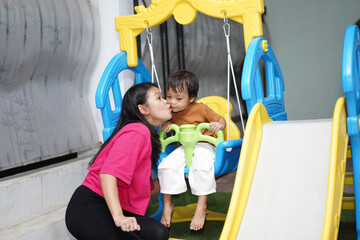 Obraz premium Mother Giving Her Son a Kiss on the Swing