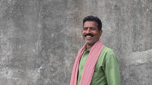 Cheerful rural indian farmer standing against plain grey background
