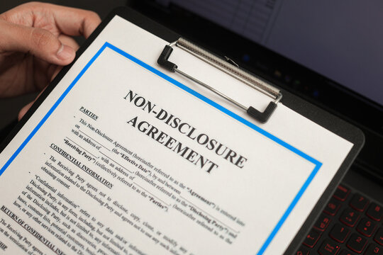 Close up view showing serious non disclosure agreement document clipped on clipboard being reviewed by worker before signing contract