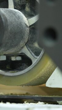 Macro shot of a heavy duty industrial roller feeding wood through a planer or sander in a professional woodworking facility.