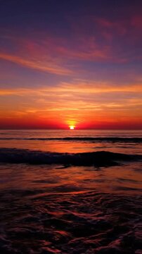 Vibrant sunset colors illuminate the sky and ocean waves at dusk.