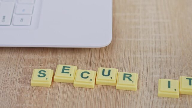 Stop motion animation shows "SECURITY" spelled out using yellow game tiles near laptop