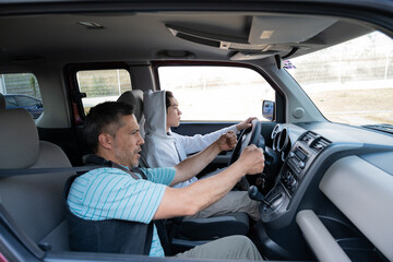 Parent teaching proper wheel grip and control for road obstacles to his son.