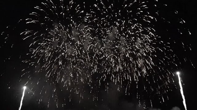 Spectacular white fireworks light up the dark sky, forming a cheerful smiley