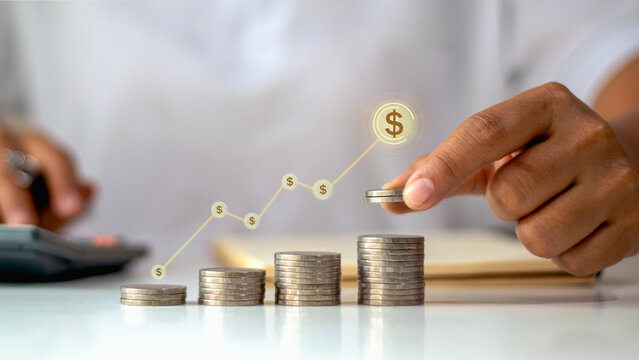 Businessman hand stacking coins with growing financial graph and dollar icons, concept of investment, profit, business success, and money savings growth.
