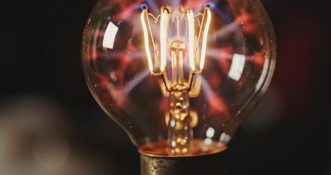 Close-up of a vintage light bulb showcasing intricate filament design and glowing plasma in the background