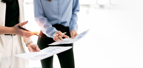Close-up of business professionals analyzing financial documents and charts in a bright office.